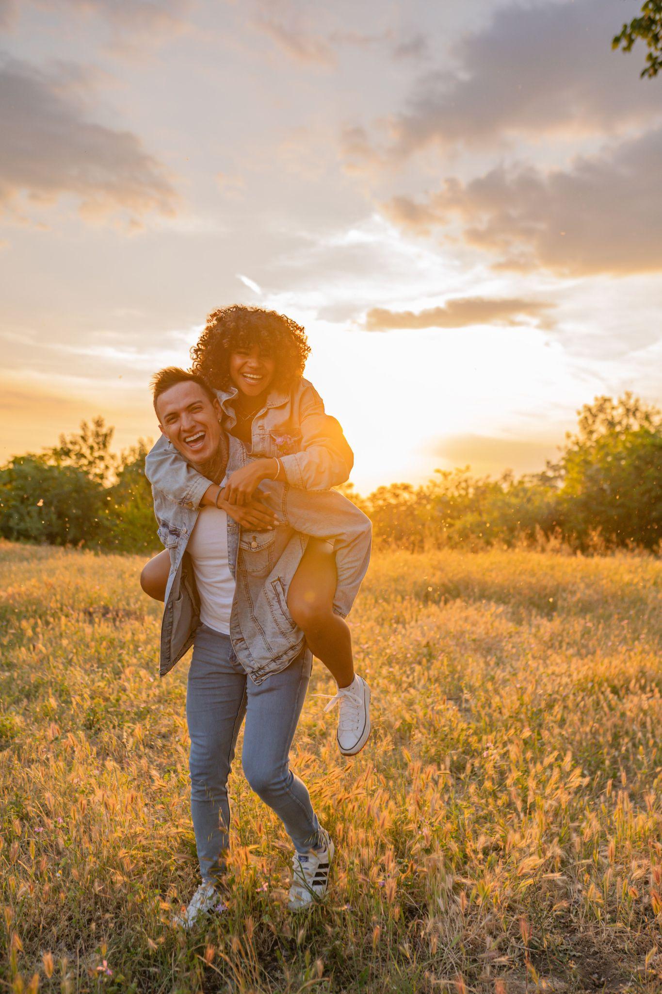 A couple laughing in a golden field at sunset