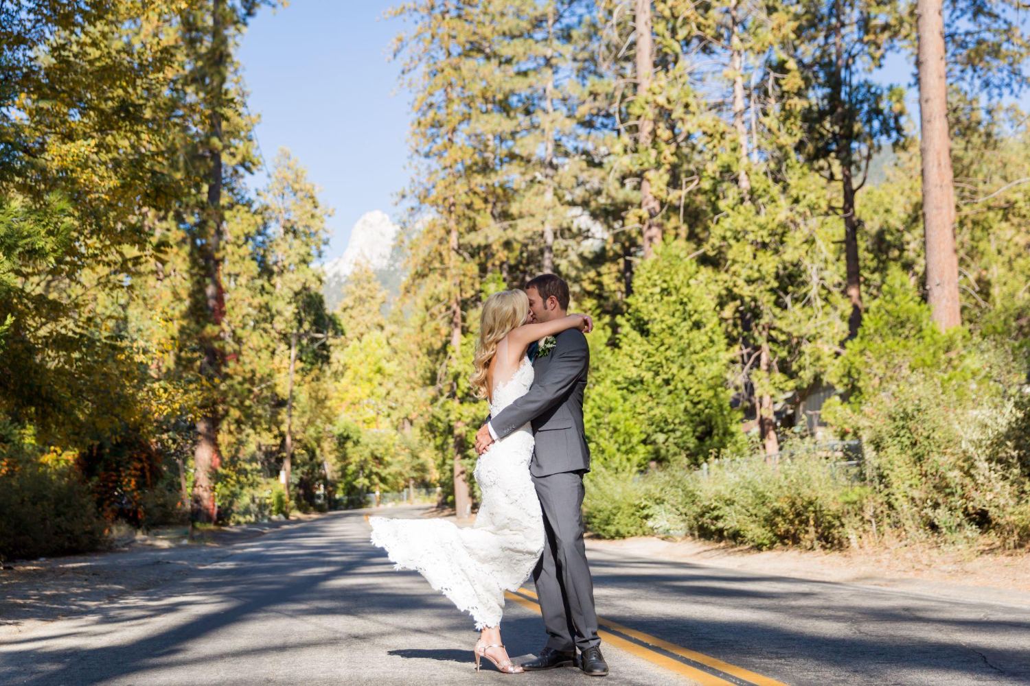 Two figures on a road through tall trees