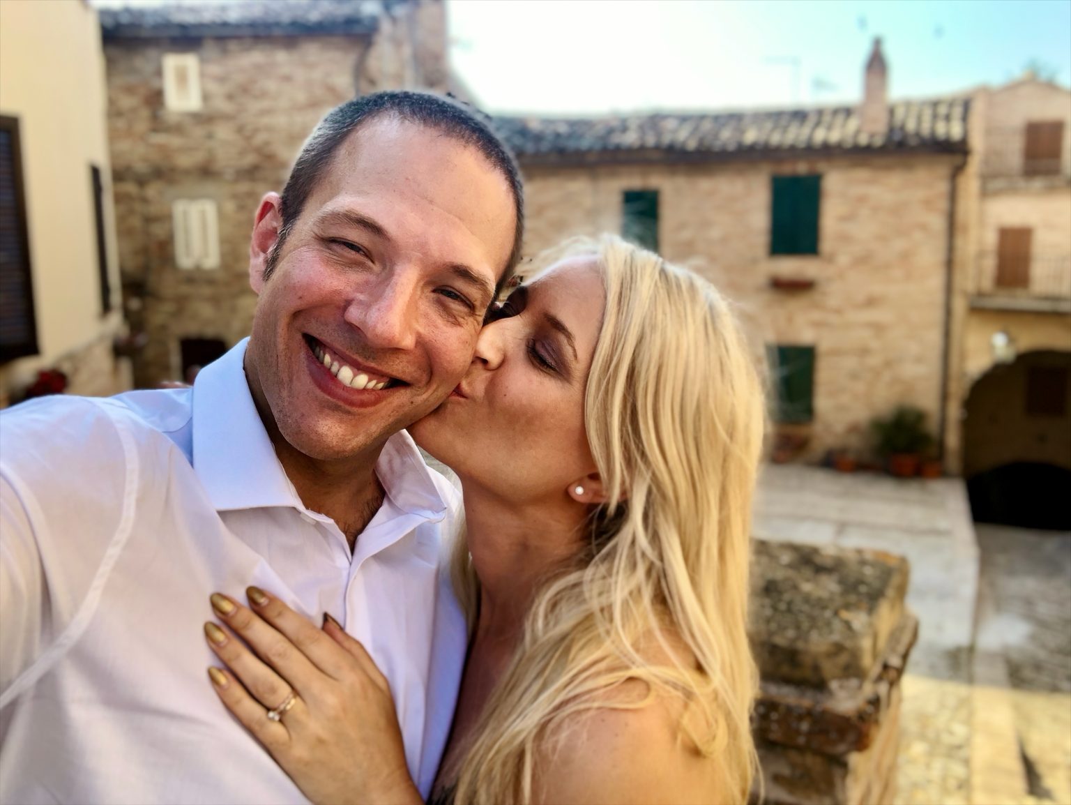 Violet kissing Jason on the cheek on a golden evening in an Italian village