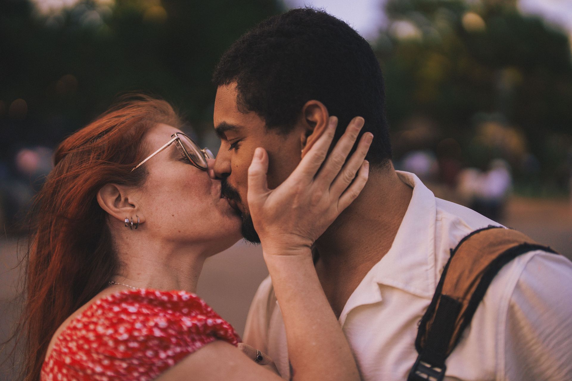 A couple kissing tenderly at golden hour, she cradling his face in her hands
