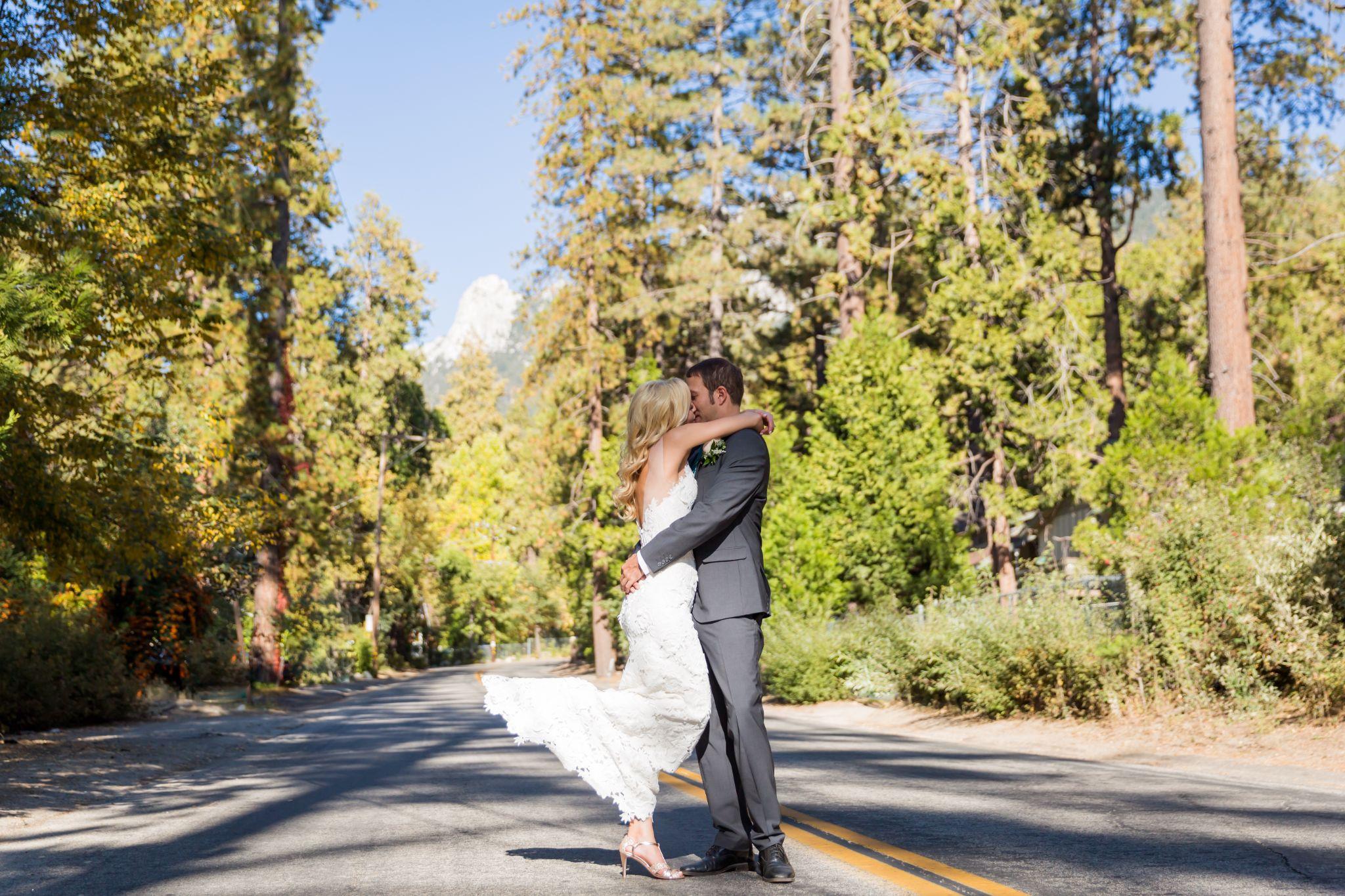 Two figures on a road through tall trees